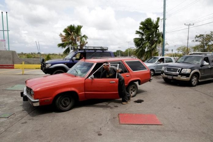A man pushes his car after running out of gas at a gas station of Venezuelan state oil company PDVSA in Maturin